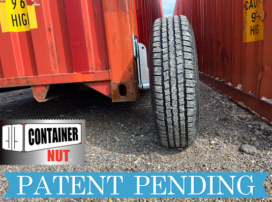 A close-up of a tire using EZY Wheels by Container Nut situated between two red shipping containers on gravel ground. The logo "Container Nut" is on the bottom left, and the text "Patent Pending" is displayed in blue across the bottom. Yellow caution signs are visible on the containers.