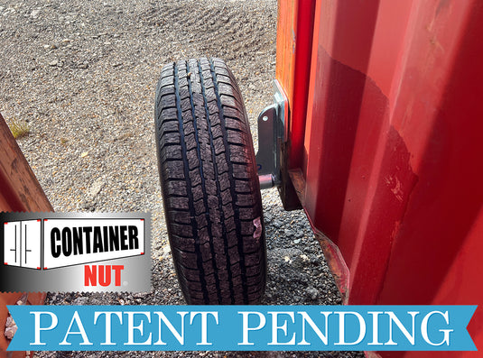 A close-up of a tire using EZY Wheels by Container Nut situated between two red shipping containers on gravel ground. The logo "Container Nut" is on the bottom left, and the text "Patent Pending" is displayed in blue across the bottom.