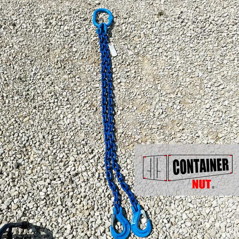 Load image into Gallery viewer, A Chain Sling from Container Nut, featuring a blue chain with two hooks and a circular ring, is laid out on a gravel surface. A partially visible label is attached to the chain.
